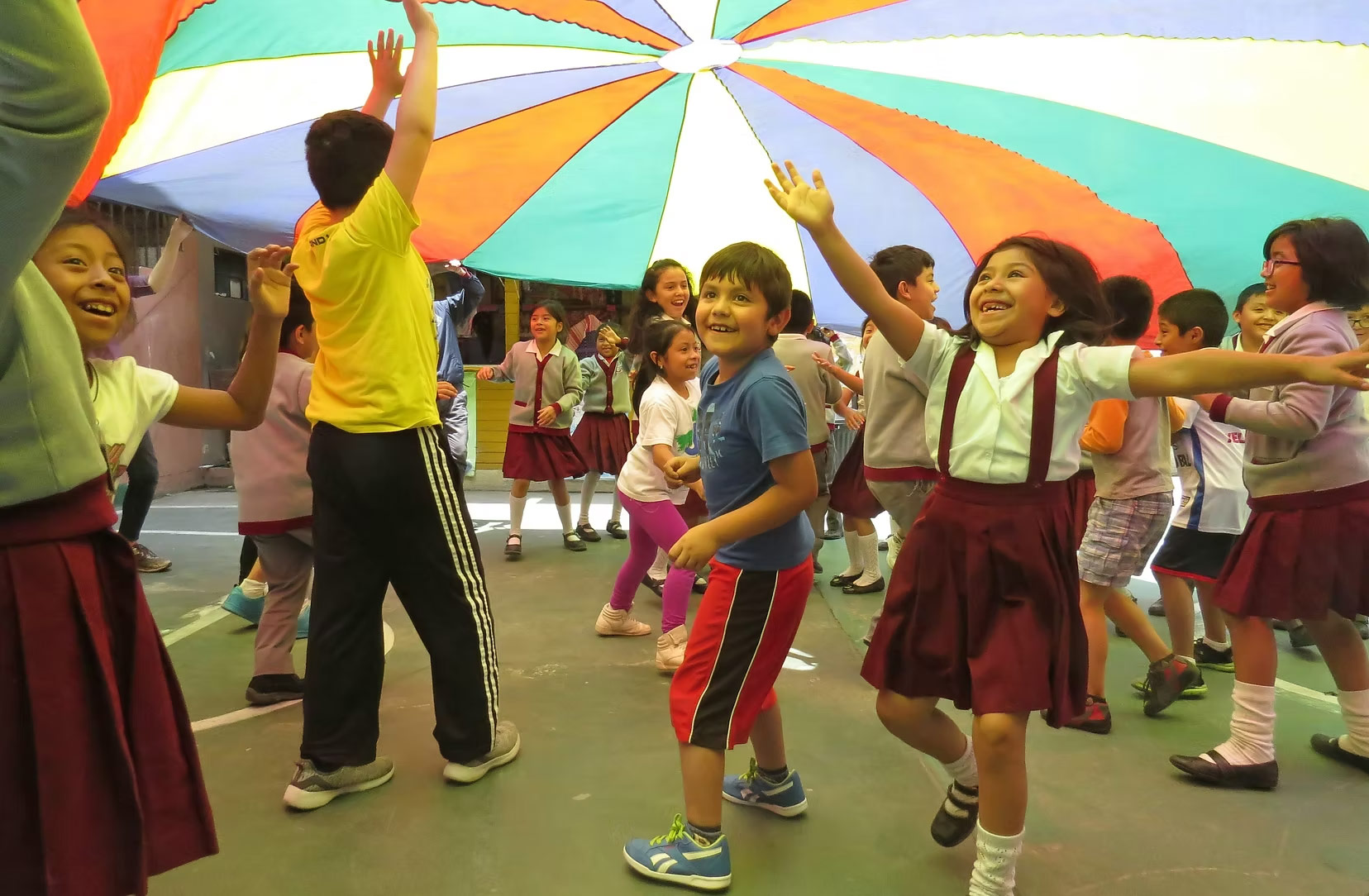 a group of students play beneath a colorful parachute