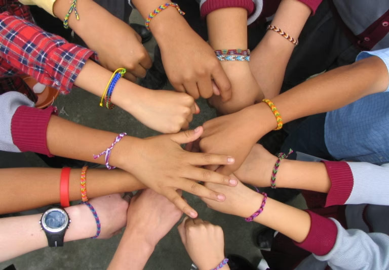 students huddle with their hands overlapping in the middle